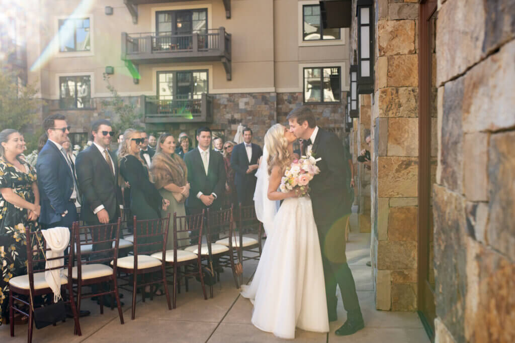 A bride and groom share their first kiss on the terrace of the Four Seasons at their destination wedding in Vail, Colorado.