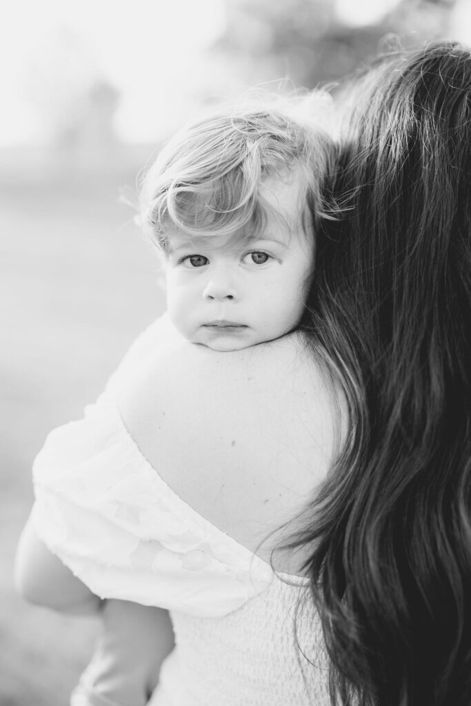 At a maternity session in Doylestown, Pennsylvania, a pregnant mother holds her older child over her shoulder.