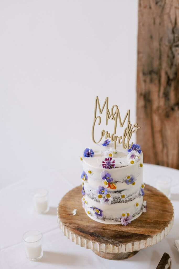 A close-up of the couple's wedding cake, adorned with purple, white, and peach flowers at Riverdale Manor in Lancaster, Pennsylvania.