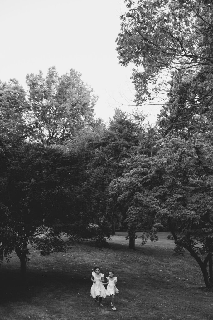 A black and white image of two flower girls running in a field at Riverdale Manor in Lancaster, Pennsylvania.