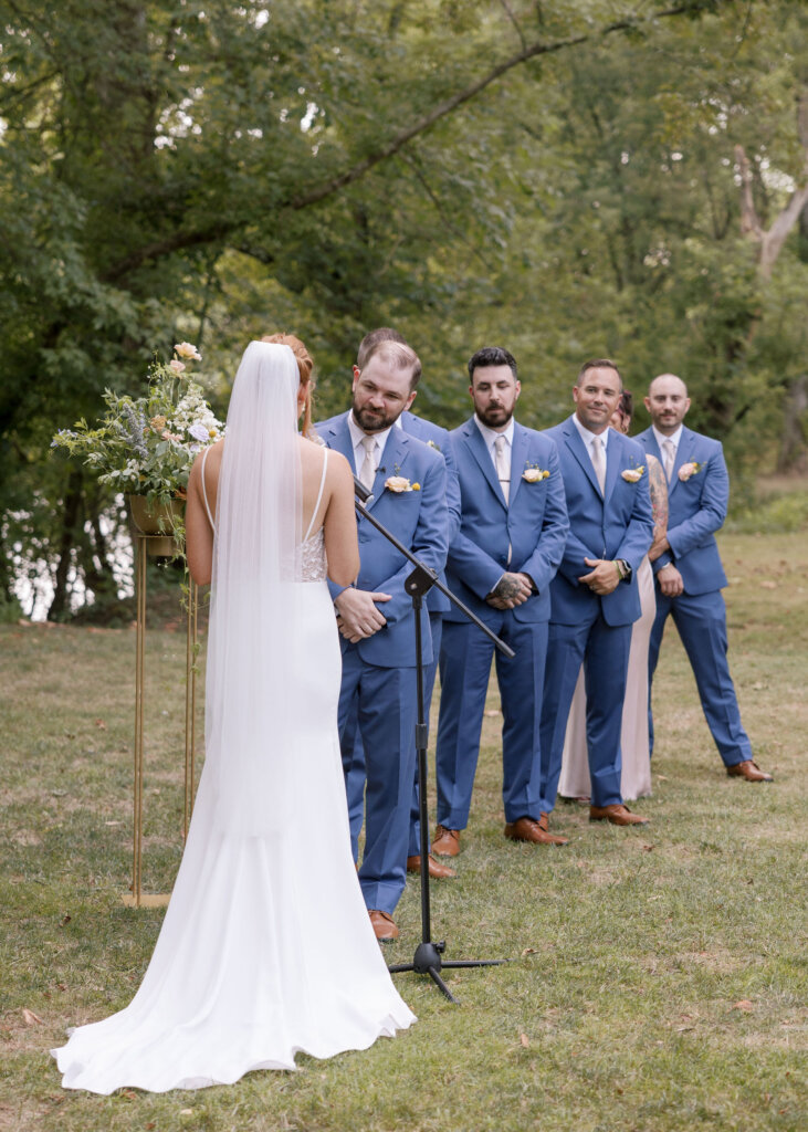 The bride reads her vows as the groomsmen look on in the background during their ceremony at Riverdale Manor in Lancaster, Pennsylvania.