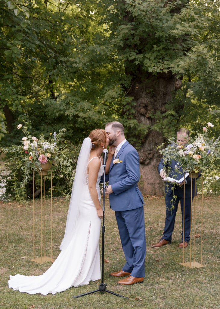 The bride and groom kiss for the first time as a married couple at their outdoor ceremony at Riverdale Manor in Lancaster, Pennsylvania.