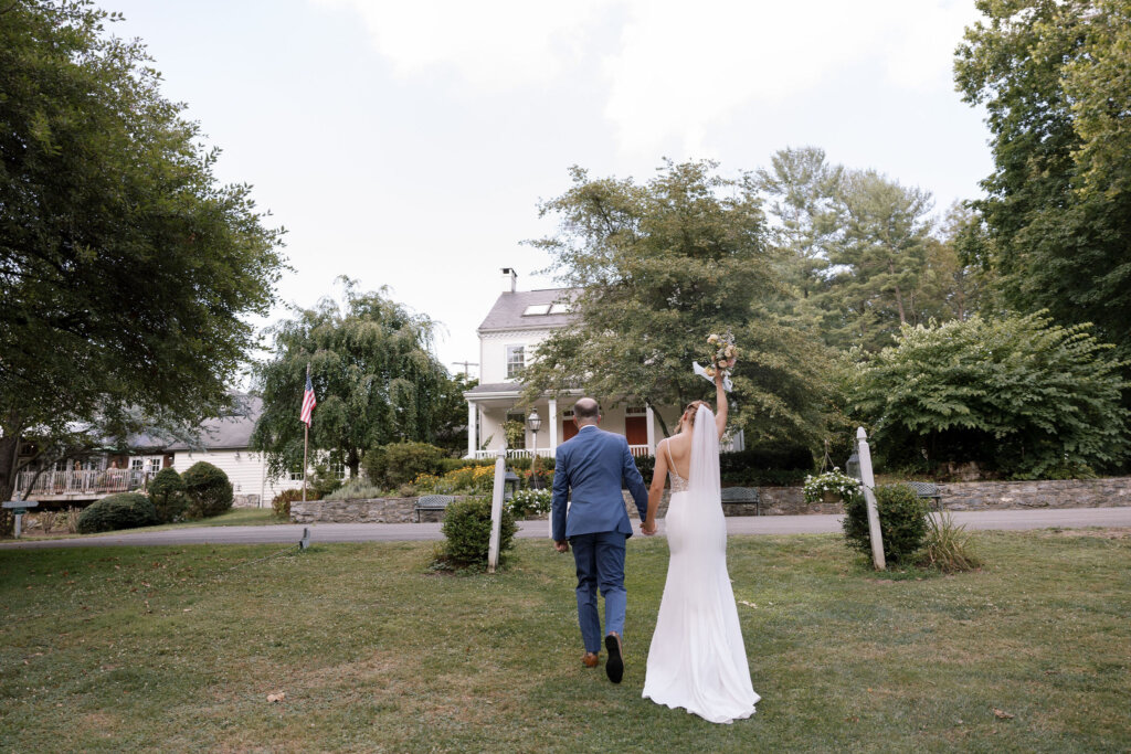 The bride and groom walk hand-in-hand toward the main house of Riverdale Manor in Lancaster, Pennsylvania.