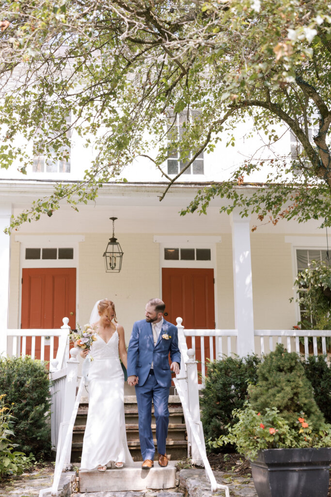 The bride and groom walk down the steps from the main house of Riverdale Manor in Lancaster, Pennsylvania after finishing their first look.