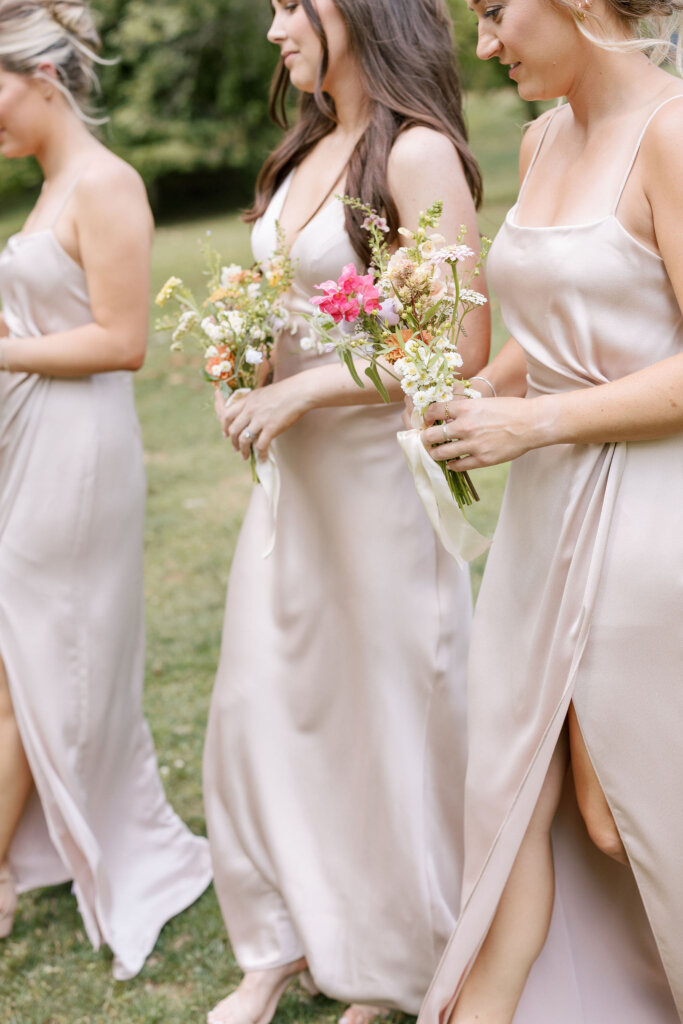 Bridesmaids in champagne dresses walk to the ceremony at Riverdale Manor in Lancaster, Pennsylvania.