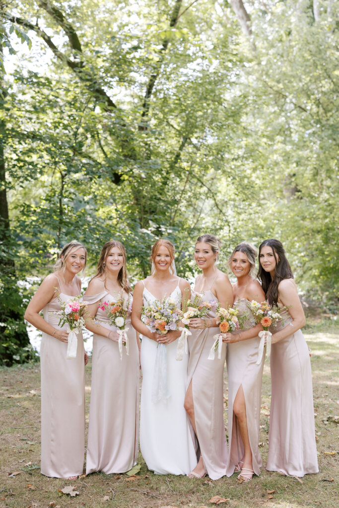 The bride poses for a portrait with her bridesmaids in the afternoon shade on her wedding day at Riverdale Manor in Lancaster, Pennsylvania.