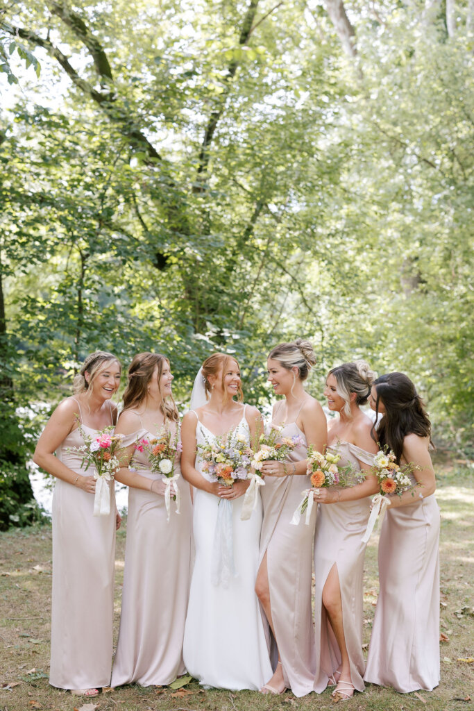 The bridesmaids smile as they look to bride at the center of the portrait during her wedding at Riverdale Manor in Lancaster, Pennsylvania.