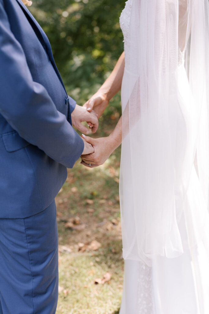 A close-up of the bride and groom holding hands while the bride's veil drapes delicately on their wedding day at Riverdale Manor in Lancaster, Pennsylvania.