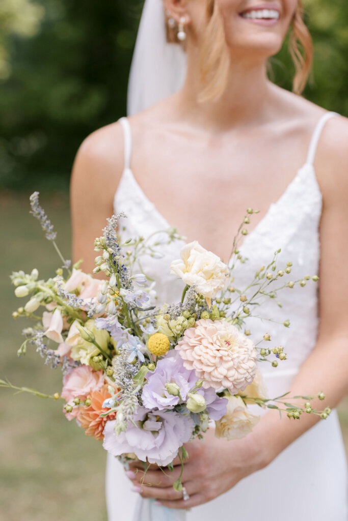 A close-up of the bride holding or bouquet of soft lavenders, creams, and peach florals at Riverdale Manor in Lancaster, Pennsylvania.