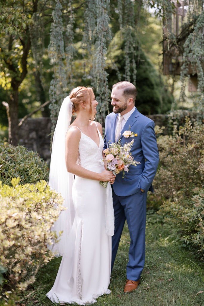 A portrait of the bride and groom smiling lovingly while she holds her bouquet on the grounds of Riverdale Manor in Lancaster, Pennsylvania.