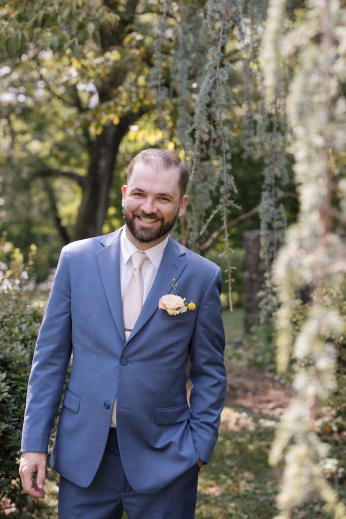 A portrait of a groom smiling in the afternoon shade on the grounds of Riverdale Manor in Lancaster, Pennsylvania.