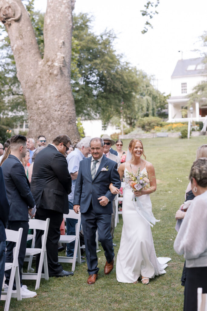 The bride's father walks her up the aisle at an outdoor wedding ceremony at Riverdale Manor in Lancaster, Pennsylvania.