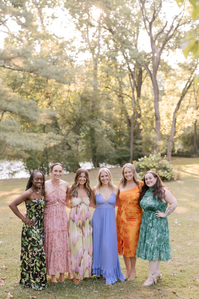 Bridesmaids and guests pose in colorful, floral dresses on the grounds of Riverdale Manor in Lancaster, Pennsylvania.