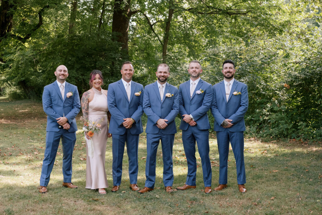 The groom poses with his groomsmen and groomswoman on the grounds of Riverdale Manor in Lancaster, Pennsylvania.