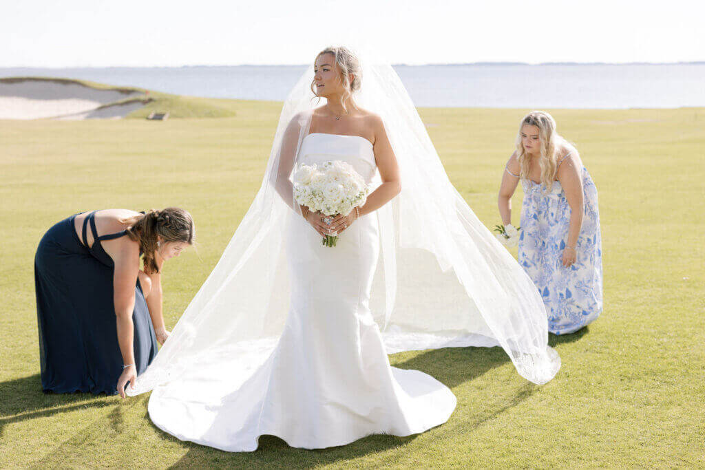 The bridesmaids in printed dresses help with the bride's veil at the Rehoboth Beach Country Club.