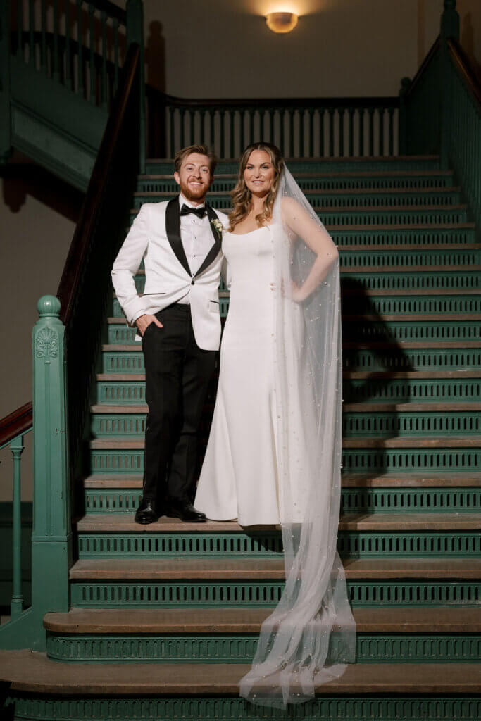 The bride and groom have a candid moment on the amazing turquoise steps at the Crystal Team Room by Finley Catering.