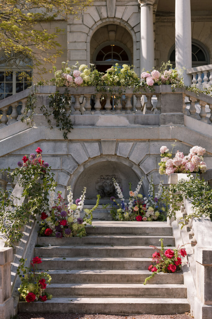Lush florals drape the exterior of Elkins Estate for a ceremony outside by the grand staircase.